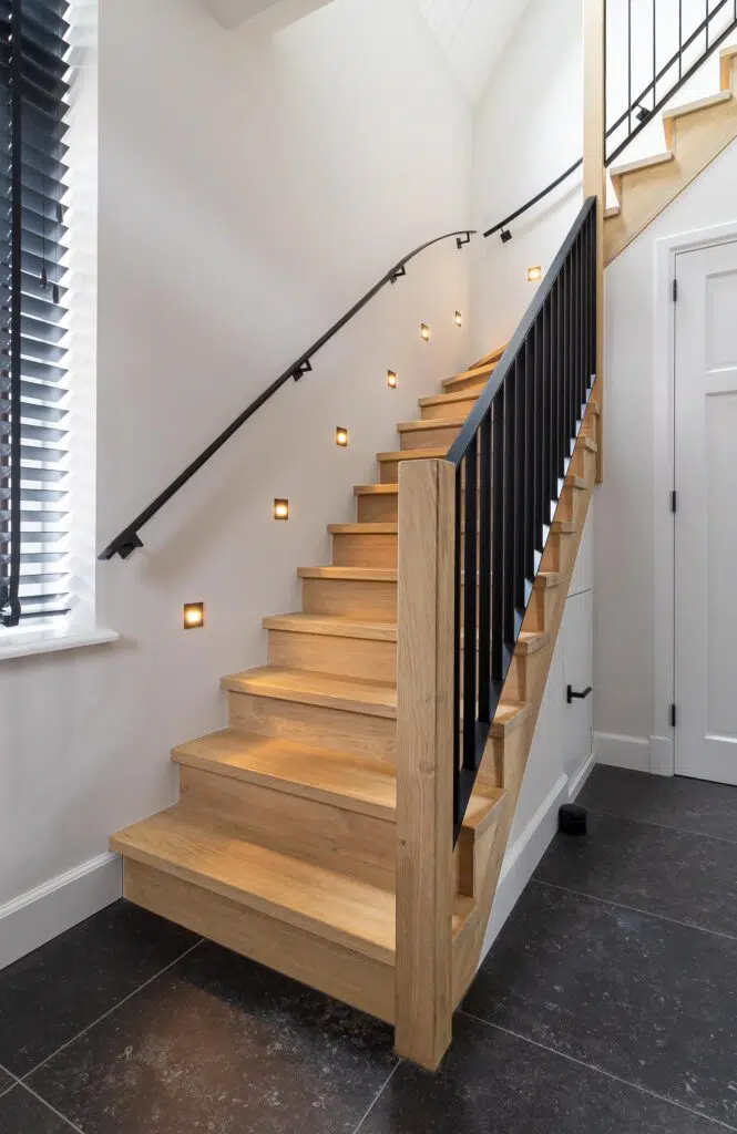 Moderne eikenhouten trap met zwart stalen hekwerk en verlichting